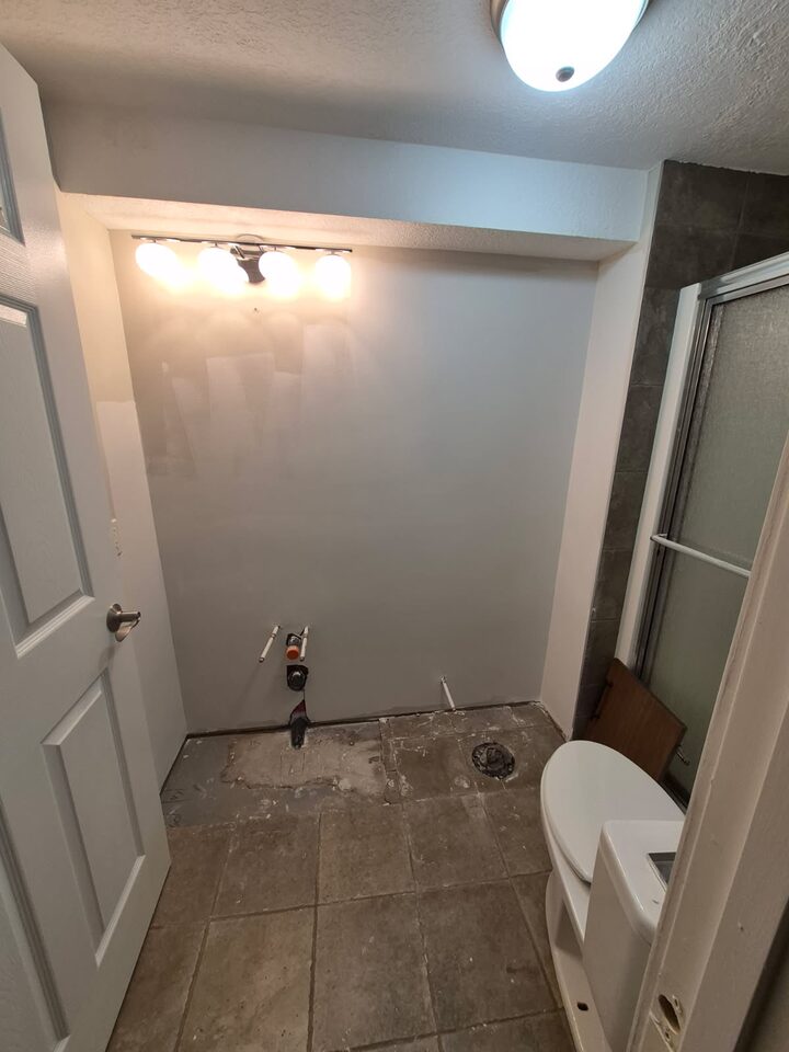 Before photo of the vanity wall in a Chinook Park Calgary bathroom before peel-and-stick wallpaper installation