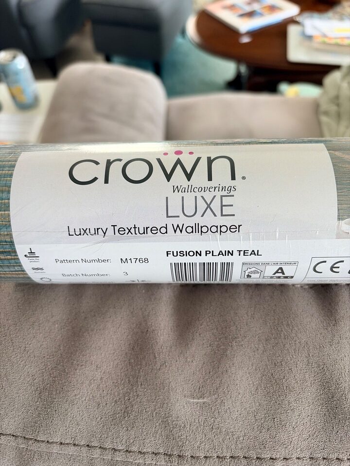 Roll label of Crown Wallcoverings LUXE Fusion Plain Teal M1768 textured wallpaper used in a Huntington Hills, Calgary living room