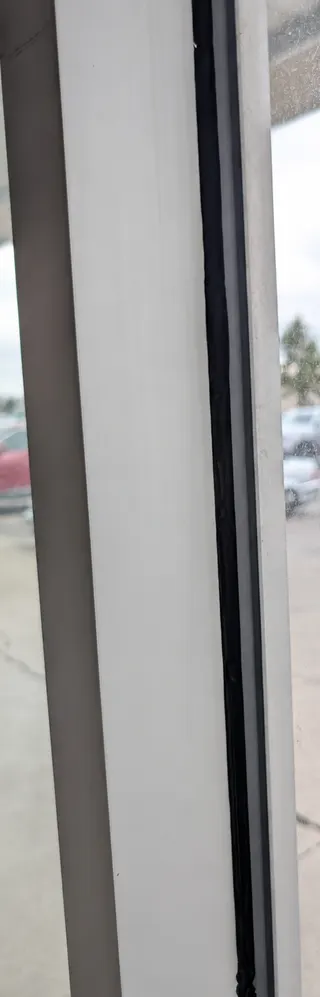 Close-up showing the width and surface of a black silicone bead along the window edge