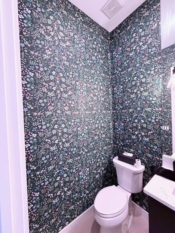 Rifle Paper Co Wildwood wallpaper in Hunter covering the powder room walls behind the toilet in an Altadore, Calgary home