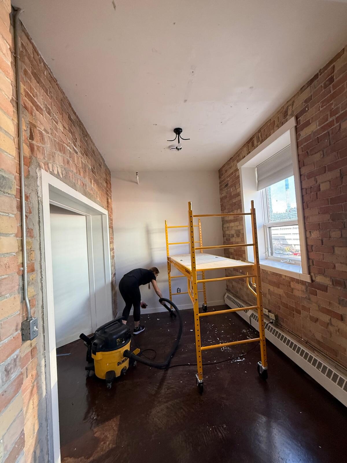 Lewis Lofts loft in Calgary's Beltline after wall mural and ceiling wallpaper removal, with scaffolding, exposed brick and cleanup underway