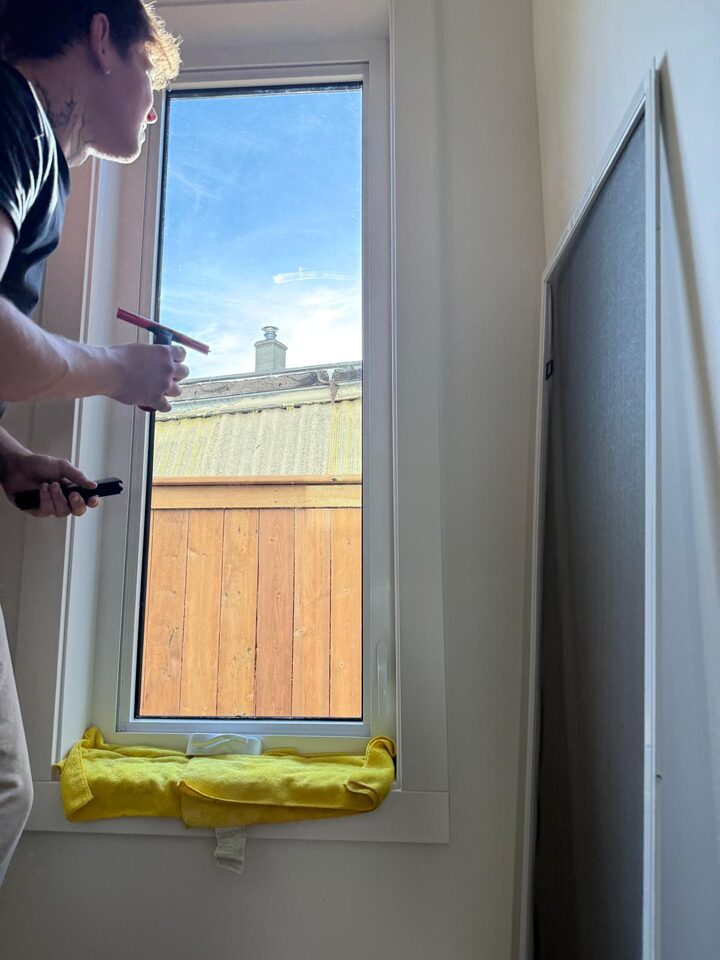 Tall clear casement window in a Bridgeland, Calgary new build looking straight at a neighbour's fence and roof before dusted crystal privacy film