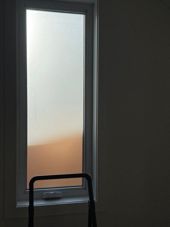 Dusted crystal frosted window film glowing in evening light on a casement window in a Bridgeland, Calgary new build