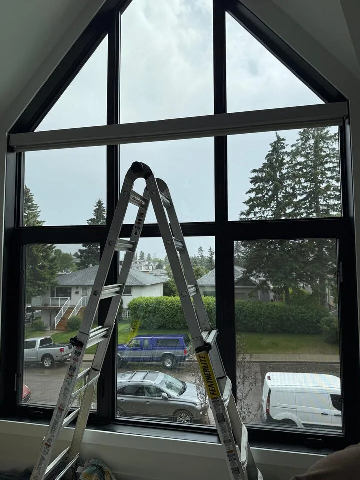Full-height after view of solar window film on a tall angled black-frame window in Capitol Hill NW Calgary