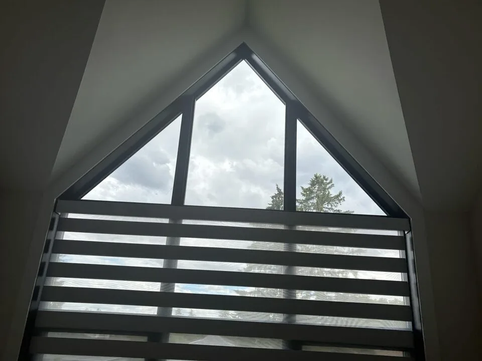 Tall angled black-frame window finished with solar window film for glare control in Capitol Hill NW Calgary