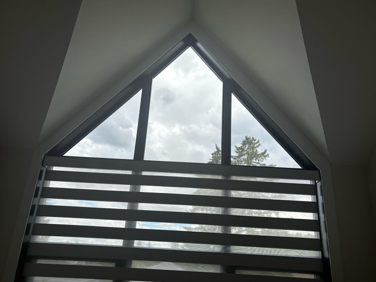 Tall angled black-frame window finished with solar window film for glare control in Capitol Hill NW Calgary