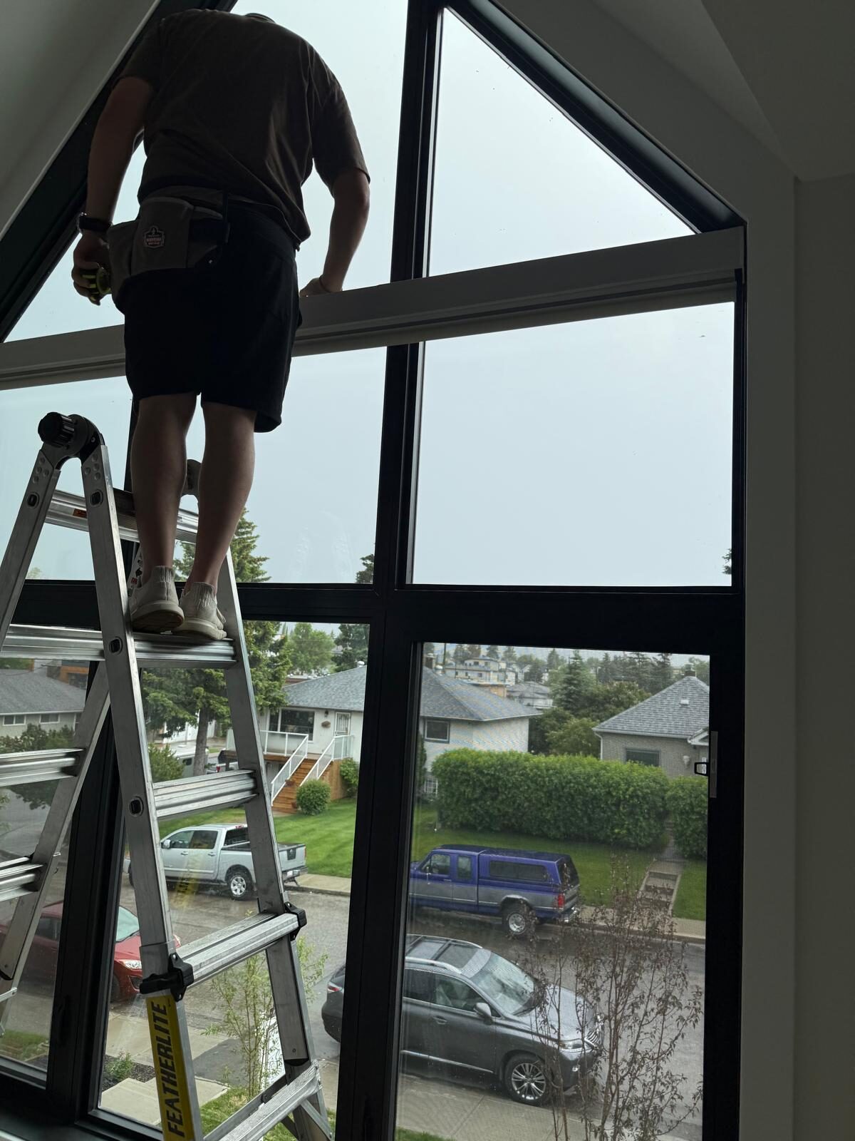 Solar window film mid-installation on a tall Capitol Hill Calgary window