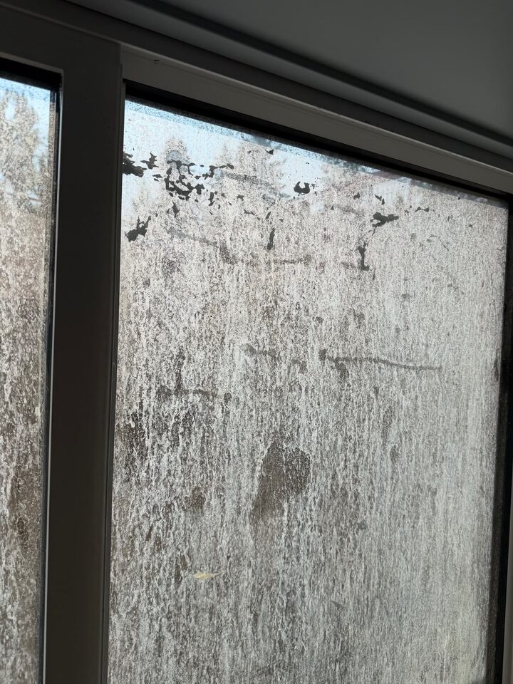 New-build glass covered in construction residue before cleaning and frosted film installation in Charleswood NW Calgary