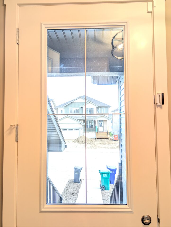 Back door glazing with prairie-grid muntins protected by 8 mil safety and security window film in a Cochrane new-build home