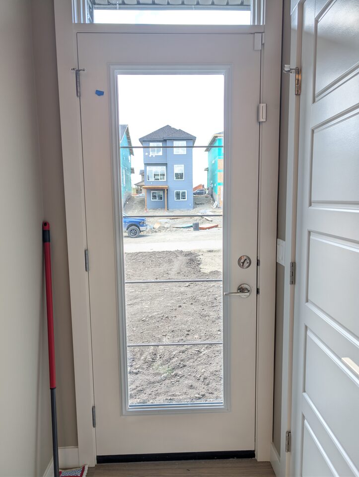 Front entry door glazing protected with 8 mil safety and security window film in a Cochrane new-build home