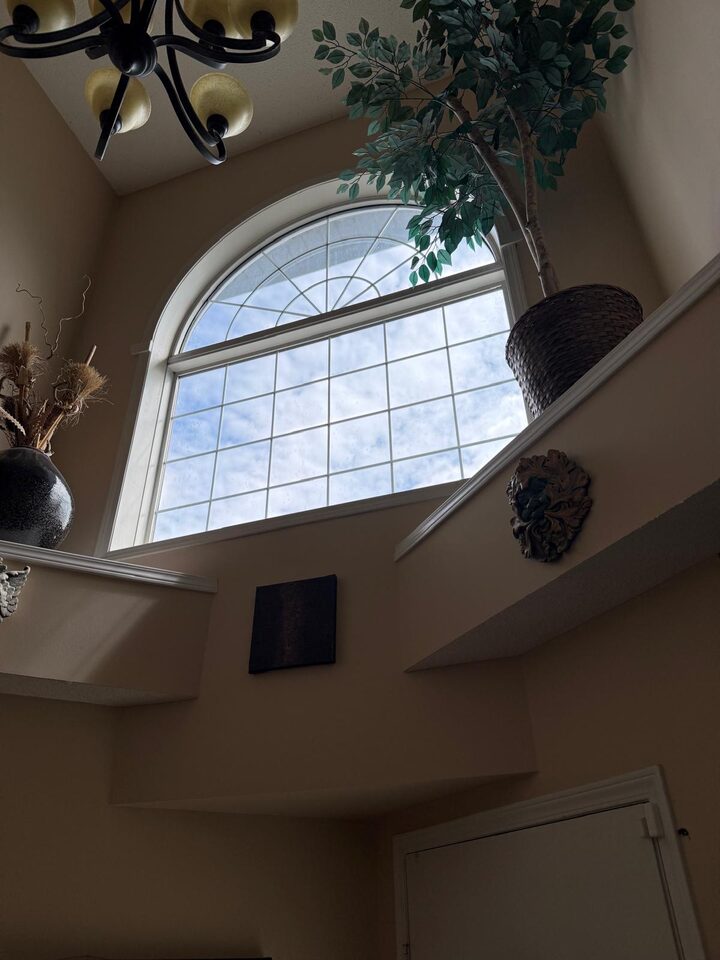 Arched foyer window with new clear solar control film softening glare after replacement in Douglasdale SE Calgary