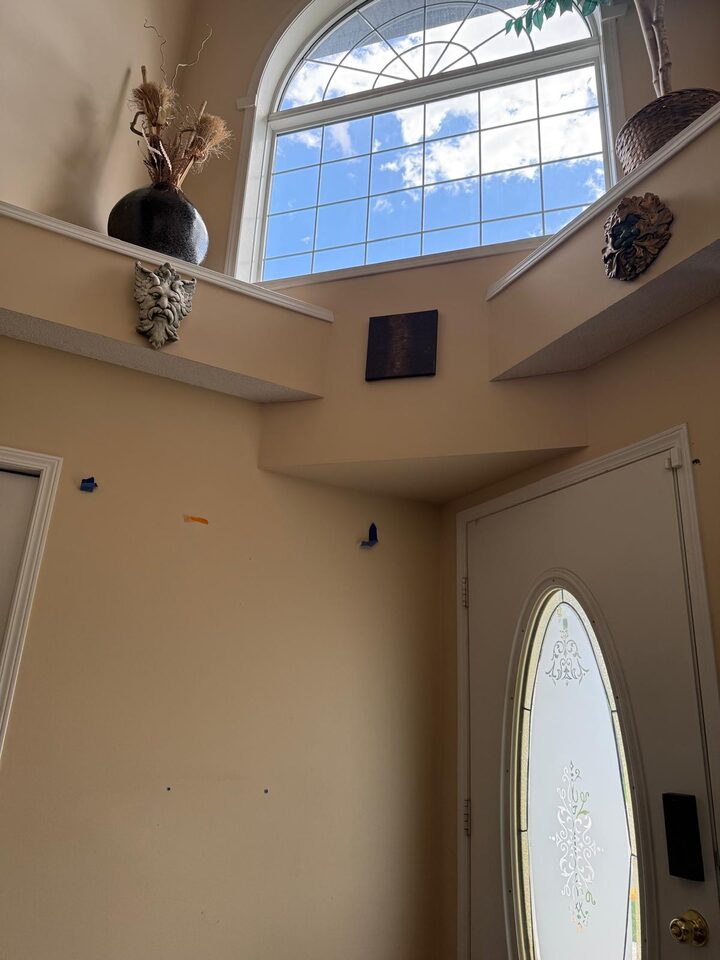 Two-storey foyer entry prepped for solar window film replacement on the arched transom window in Douglasdale SE Calgary
