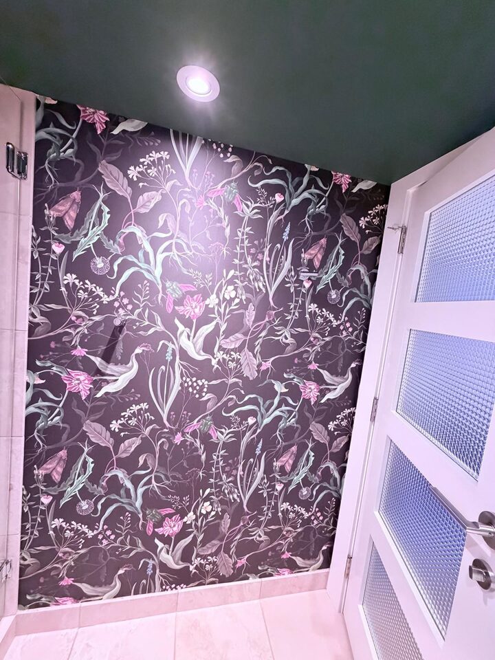 Botanical mural section with pink flowers and birds on the 60 inch bathroom wall beside the door in an Eau Claire condo, Calgary