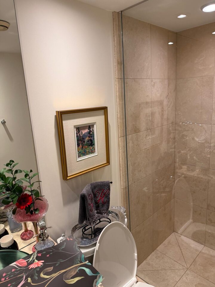 Eau Claire, Calgary condo bathroom before the mural, a cream painted wall between the vanity and the tiled shower