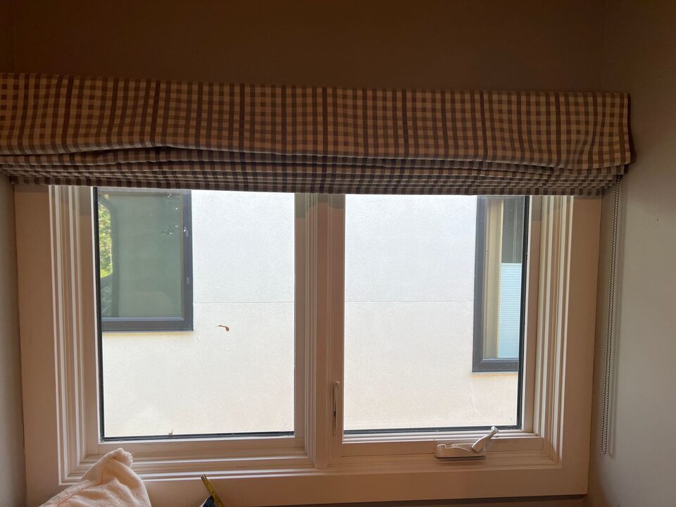Clear double casement window with a direct view into the neighbouring house before frosted privacy film in Elbow Park SW Calgary