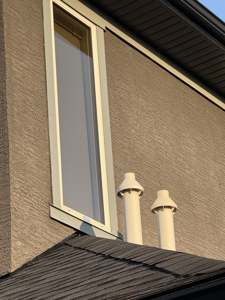 Exterior stucco gable of a Heritage Pointe home with heat-control solar window film installed on a horizontal bedroom window