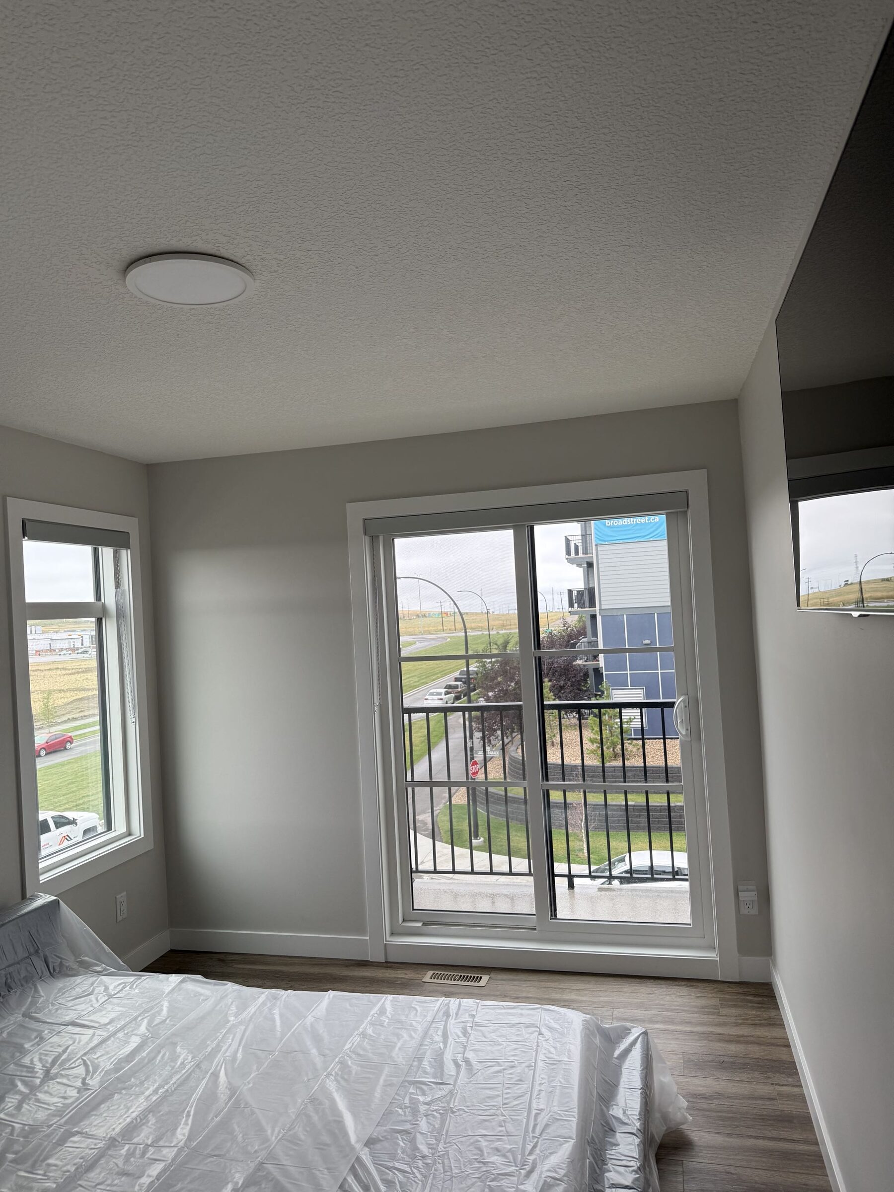 Bedroom balcony doors and adjacent window photographed on site for the Livingston solar-film project. This is a separate room, not an after photo of the kitchen.