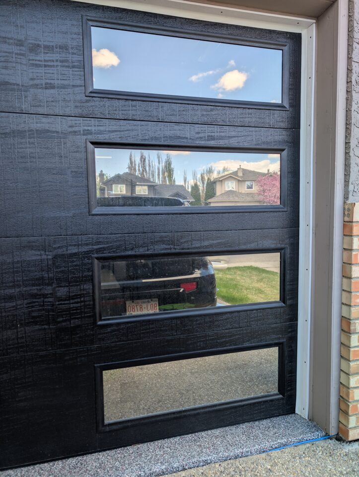 Close detail after reflective privacy window film installation on black garage door windows in McKenzie Lake Calgary