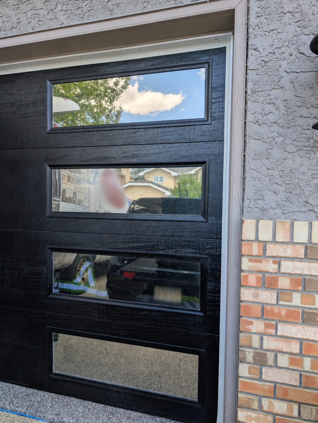 Reflective privacy window film installed on black garage door windows in McKenzie Lake Calgary