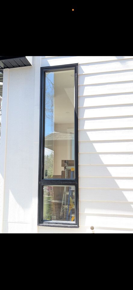 Close detail of solar window film on a tall narrow black-frame window in Mount Pleasant NW Calgary