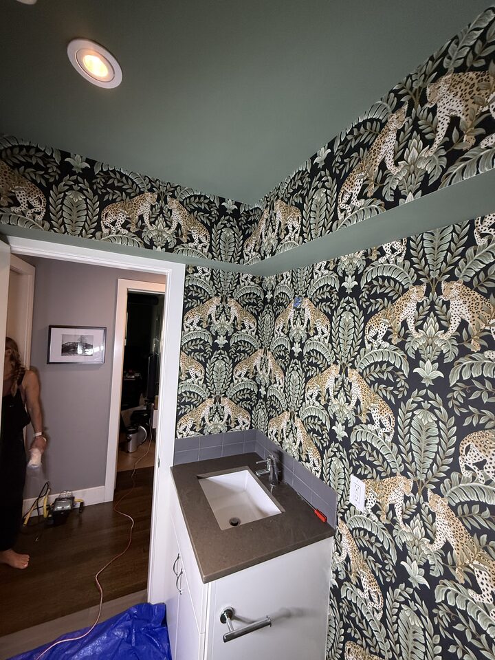 Wide view of a finished Parkland SE Calgary bathroom with leopard botanical wallpaper above tile and sage green walls