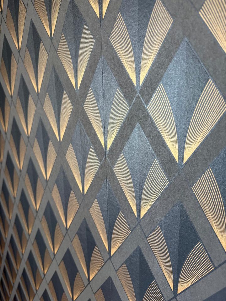 Close-up detail of gold metallic art deco diamond fan wallpaper pattern on a charcoal ground in a Calgary powder room