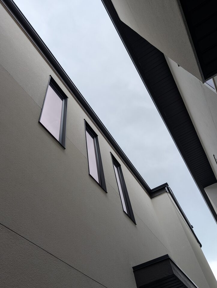 Dual-reflective solar window film on a wall of high west-facing windows in Rosscarrock, Calgary