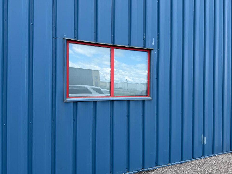 Detail of frosted privacy window film on a red-frame airplane hangar exterior window near Springbank Airport