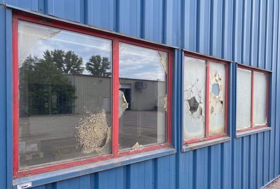 Peeling frosted privacy window film on airplane hangar exterior windows near Springbank Airport before replacement