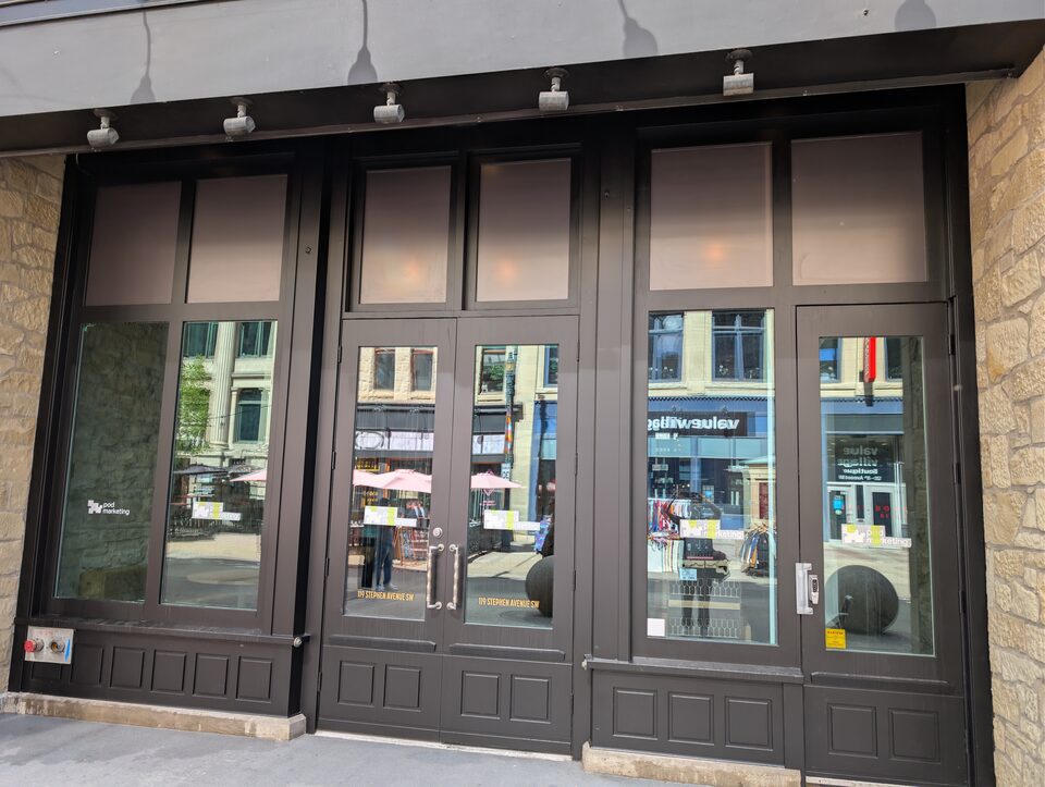 Upper storefront panels and entrance glazing photographed after the Stephen Avenue solar-film installation