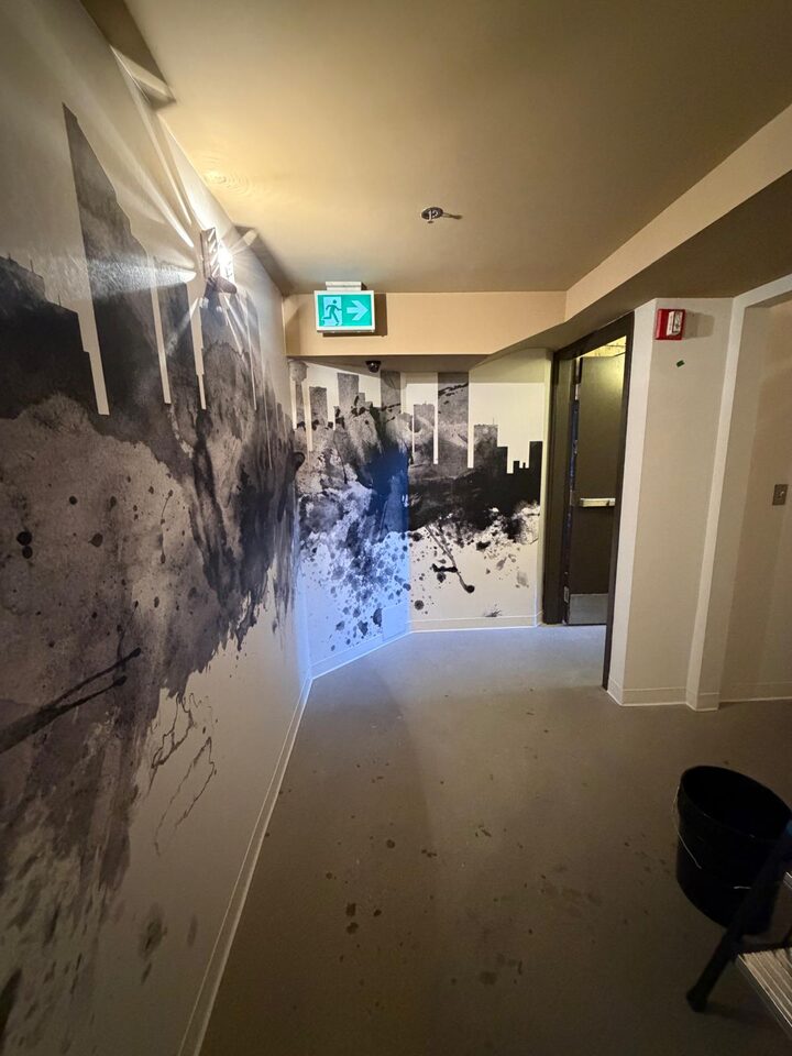 Ink-splash Calgary skyline mural wallcovering running the length of a commercial corridor toward the exit, Stephen Avenue, downtown Calgary