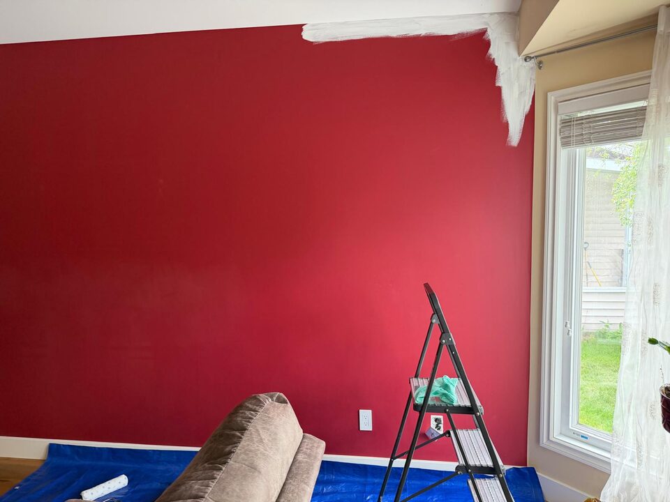 Before photo of the window side of a red living room feature wall before mural wallpaper installation in Sundance SE Calgary
