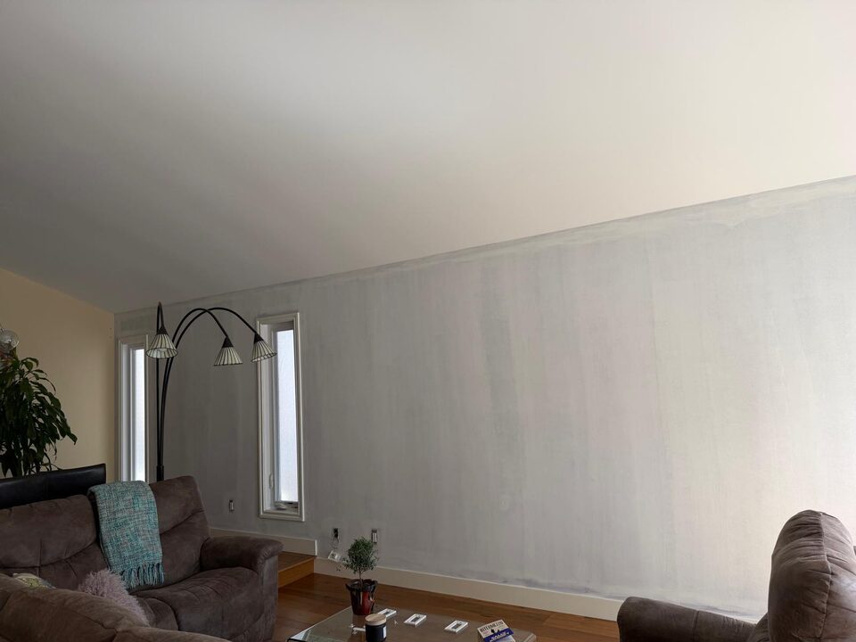 Progress photo of a primed living room feature wall before mural wallpaper installation in Sundance SE Calgary