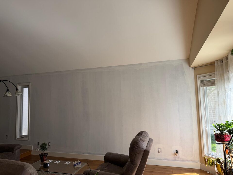 Progress photo of the primed window side of a living room feature wall before mural wallpaper installation in Sundance SE Calgary